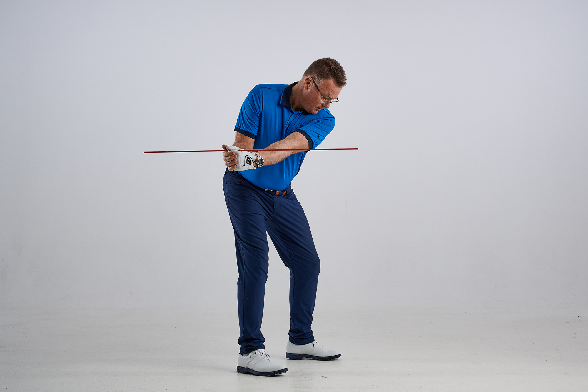 John Jacobs using an alignment stick to show the correct structure of the arms in the backswing
