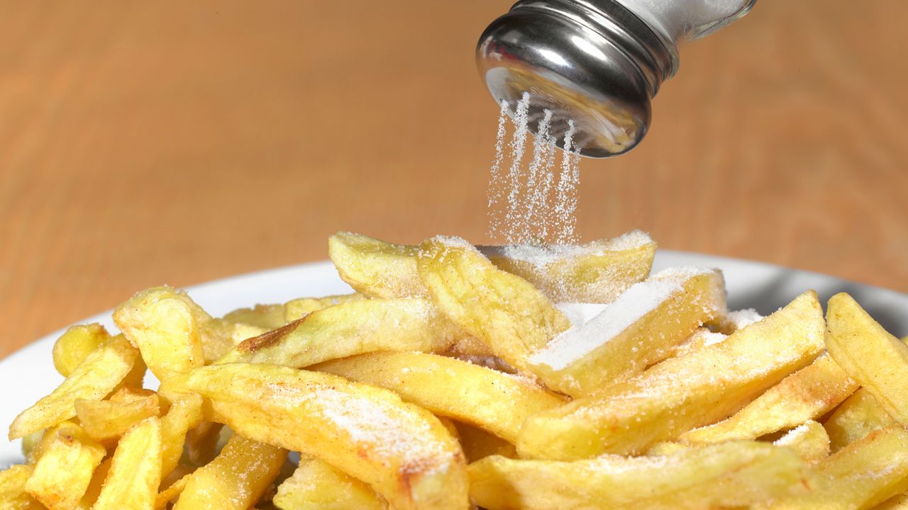 fries with salt being poured on them