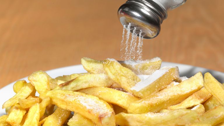 fries with salt being poured on them