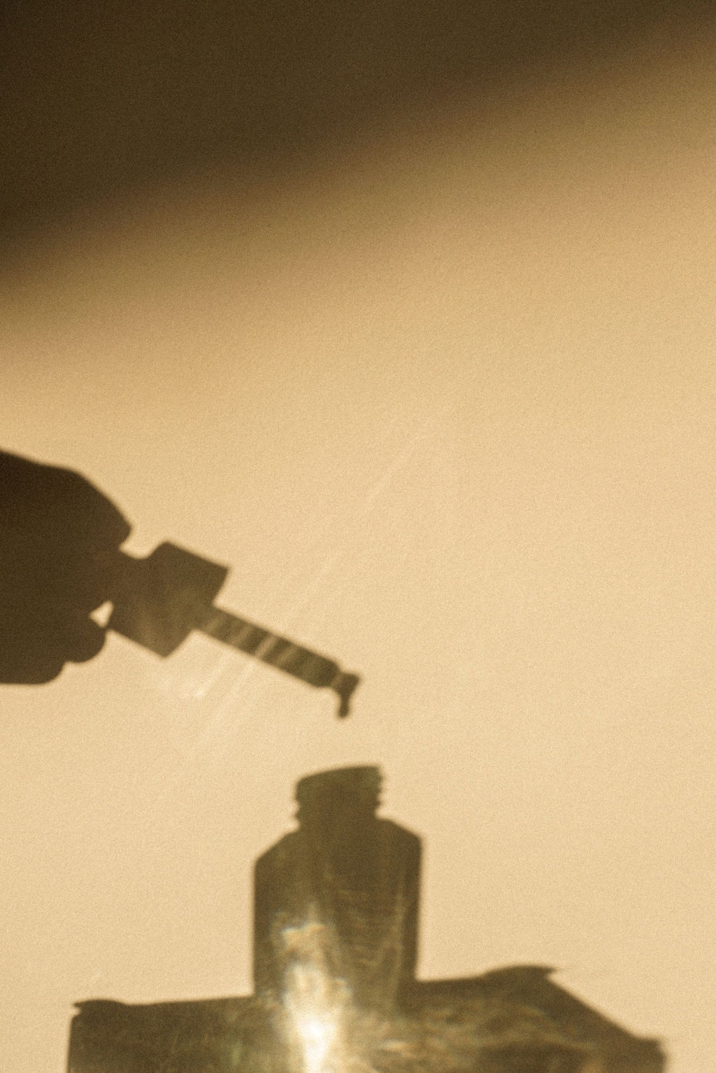 The shadow of a bottle full of face oil.