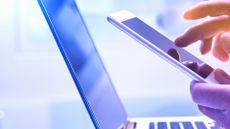 person using iPhone in front of laptop