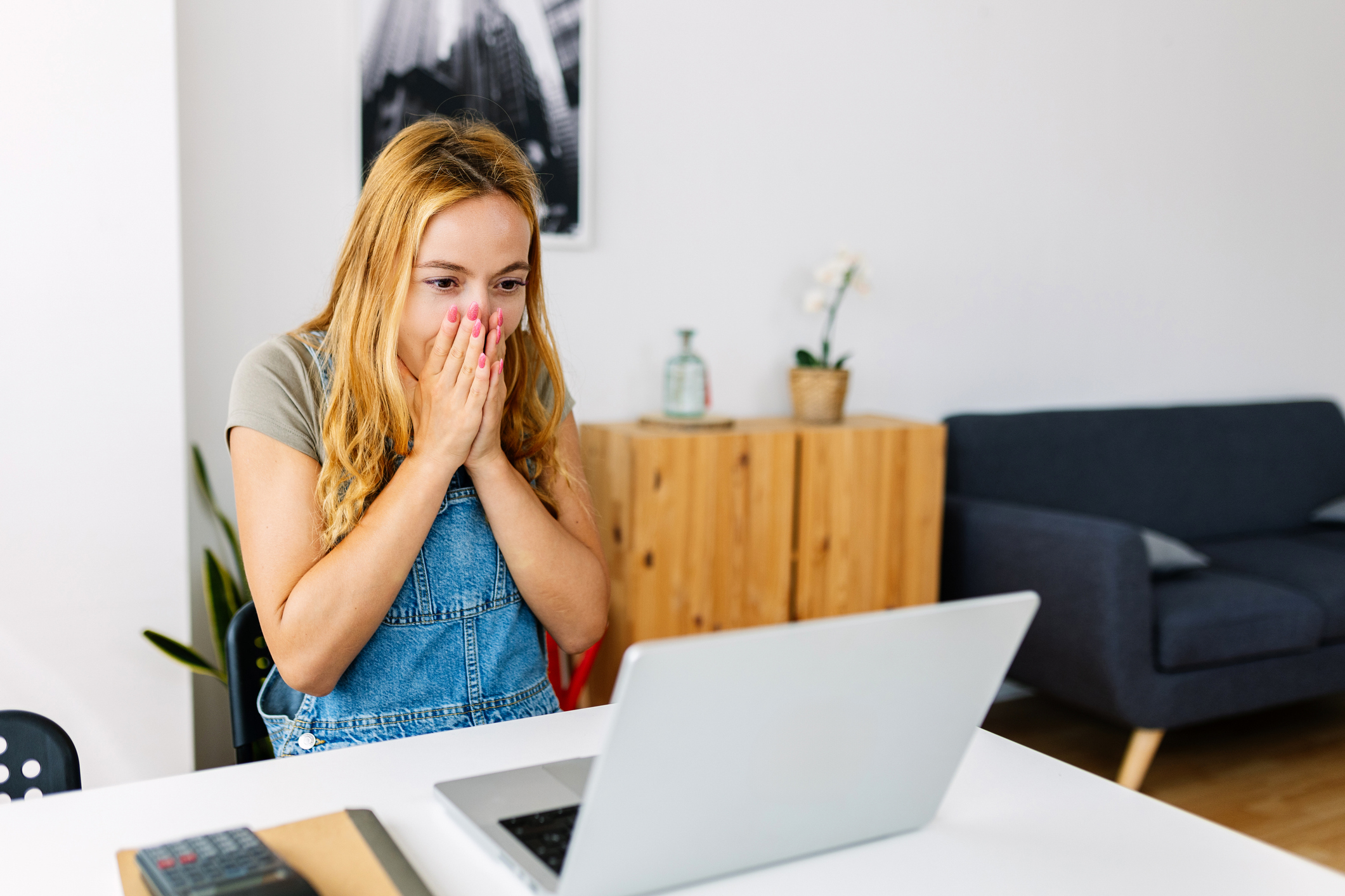 Surprised woman reading unexpected positive message on laptop at home