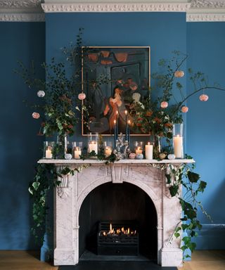 blue living room with a marble mantel with sprigs and garlands of outdoor foliage