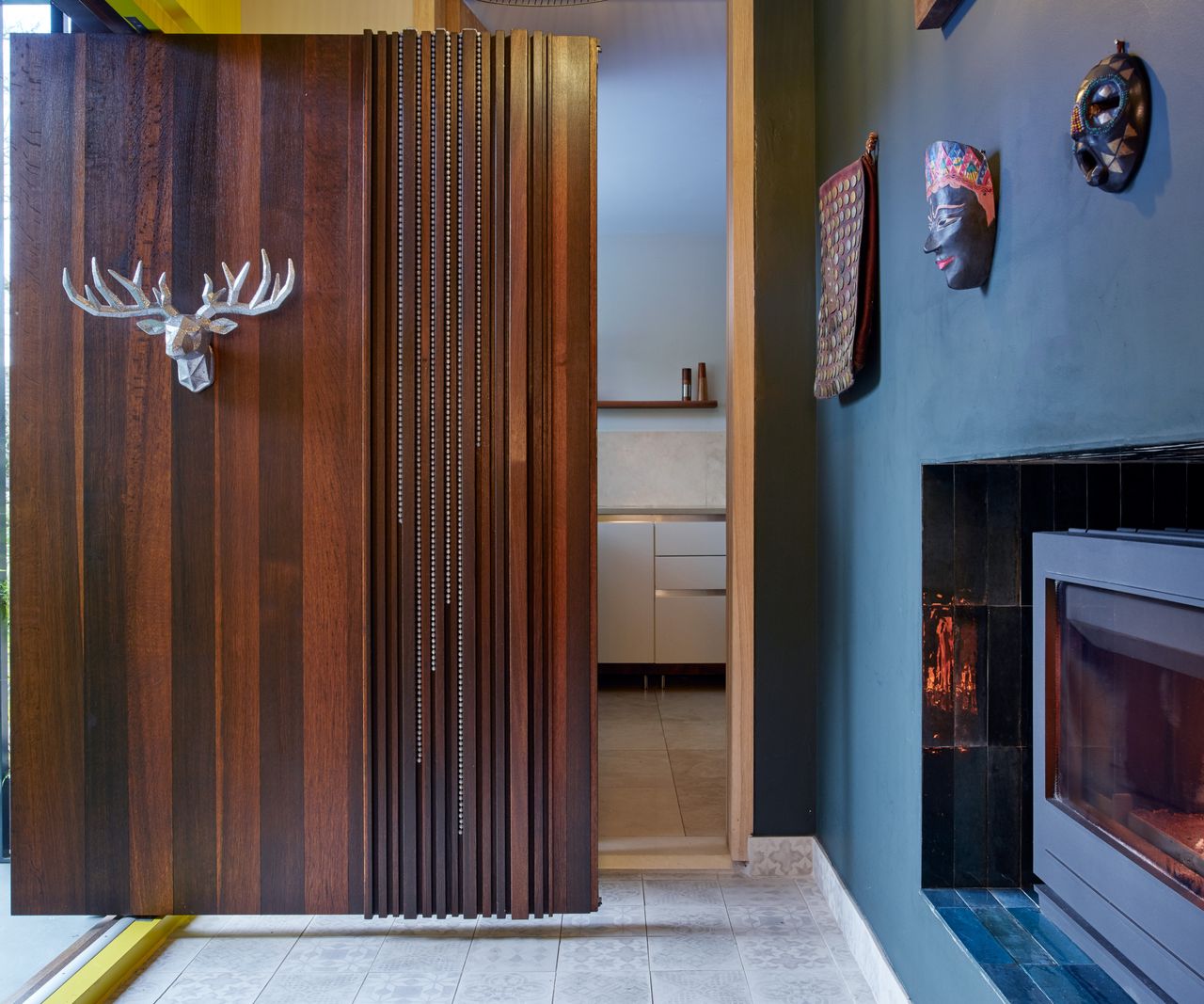large dark walnut front door with silver stag head and decor hung to side of walnut door strips
