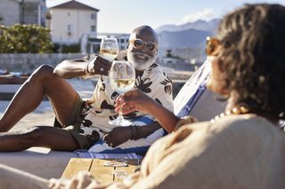 Smiling senior man toasting wineglass with mature woman during sunny day