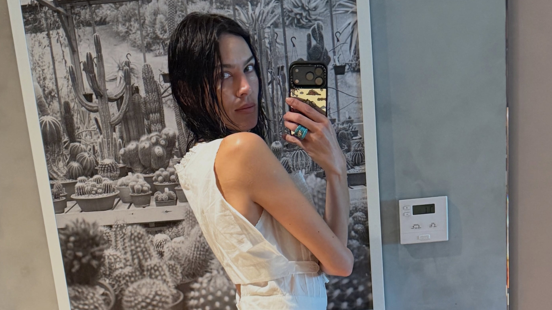 Alexa Chung takes a mirror selfie wearing camo trousers with a white cropped top.