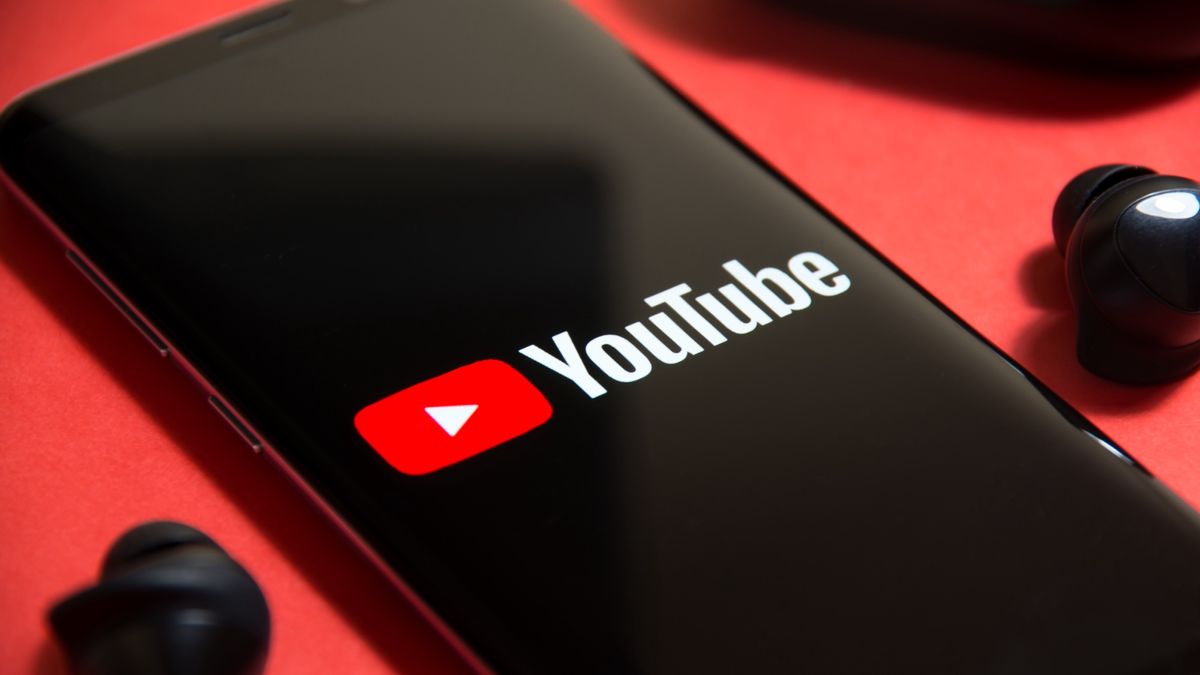 YouTube logo on smartphone flanked by earbuds