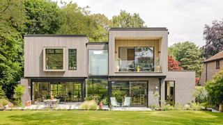 Exterior of house with boxy design and trees to the left hand side and large lawn in front