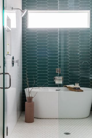 small bathroom shower with teal tiles, white bathtub, white floor tiles, glass doors