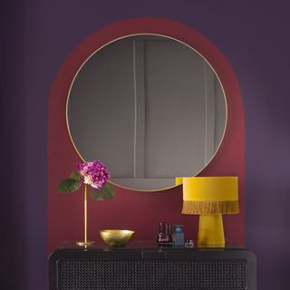 vanity area with dressing table and round mirror on wall