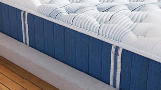 A close up of the edge of a Bear Elite Hybrid mattress showing handles and a white cover