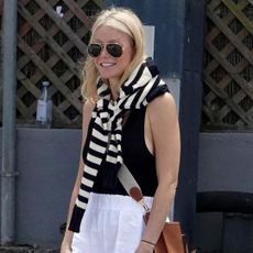 Gwyneth Paltrow in Capri wearing a sleeveless black top and white linen pants 