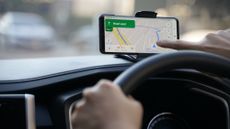 A Driver tapping on their phone screen while Google Maps is on screen