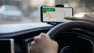 Un conductor pulsando la pantalla de su teléfono mientras Google Maps está en pantalla