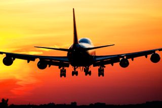 A photo of the back of a plane taking off at sunset