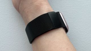 A black-coloured metal mesh watch strap wrapped around a woman's wrist.