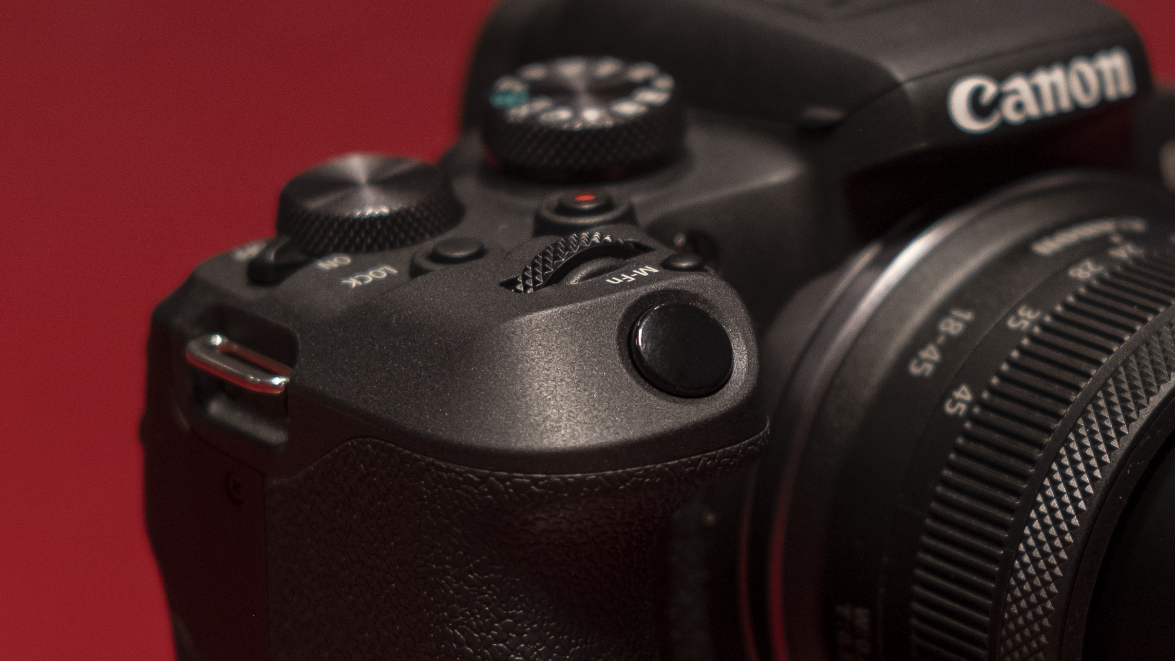 The Canon EOS R10 camera on a red surface