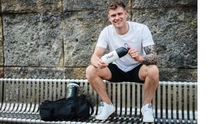 man on bench holding new Huel shaker bottle