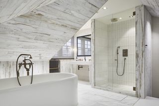 white bathroom with wooden cladding, white tub, shower, vanity unit