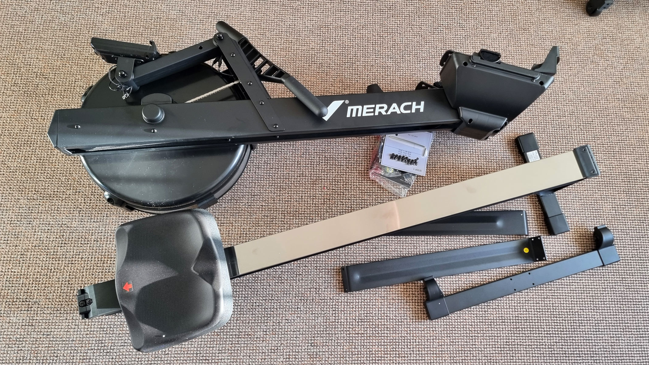 The Merach NovaRow R50 in pieces on a carpet, ready to assemble.