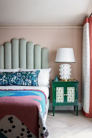 pale pink bedroom with pale green headboard, green side cabinet and texture bed side light