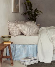 White, oatmeal and blue bedding on a bed against cream walls. 