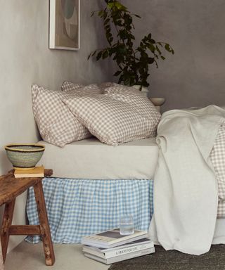 White, oatmeal and blue bedding on a bed against cream walls.