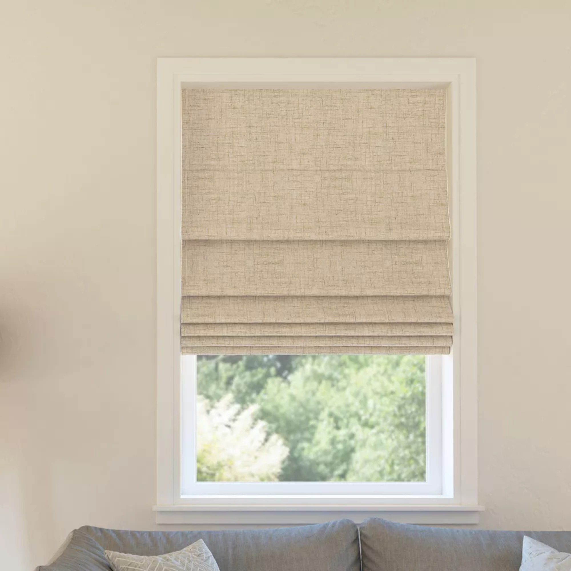 a window with a beige roman shade in front