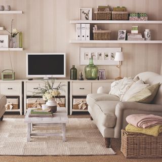 A beige living room with a striped wallpaper and wicker storage baskets dotted around the room