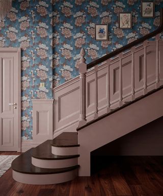 pink and blue entryway with pastel pink woodwork, laminate flooring, blue floral wallpaper, rug