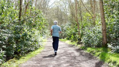 Older man runs through a green woodland path