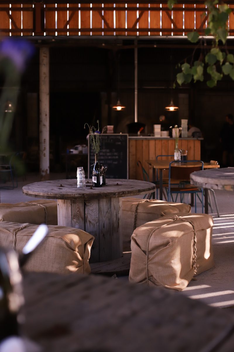 A restaurant and bar sited within a former farm barn boasts wooden furniture and jute sacks used as stools, mixed with more contemporary lighting and occasional chrome accents.