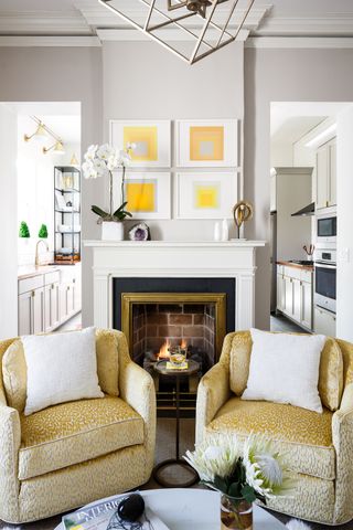 fireplace in open plan living room and kitchen flanked by two velvet chairs Bethany Adams Interiors