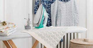 laundry room with ironing board with tea towel to show how to dry clothes indoors by ironing items