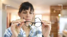 Woman looking at eye glasses in hand wondering can menopause cause dry eyes