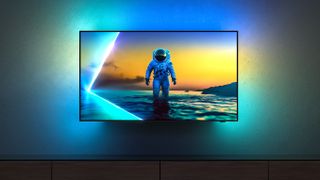 The Philips OLED810 TV mounted on a wall, with an astronaut on-screen, with Ambilight spreading light onto the wall around it