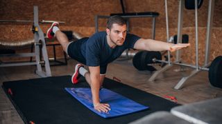 Man performs bird dog exercise in a home gym