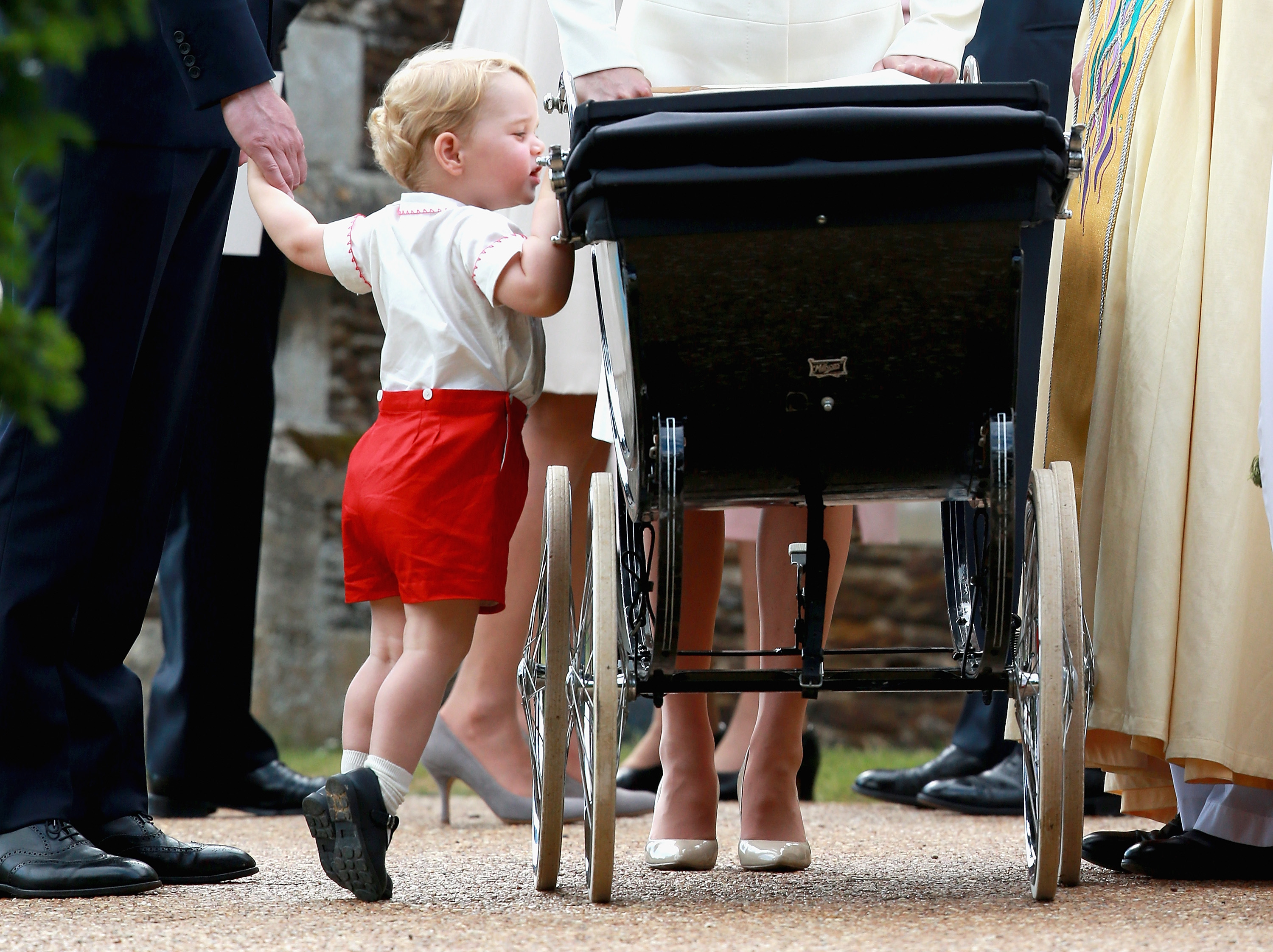 Prince George peering into Princess Charlotte's stroller at her christening