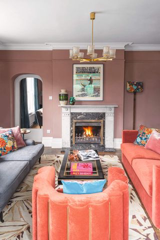 A dusky red wall in a living room, and bright orange sofas