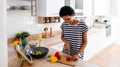 Woman smiles as she chops up vegetables in a kitchen