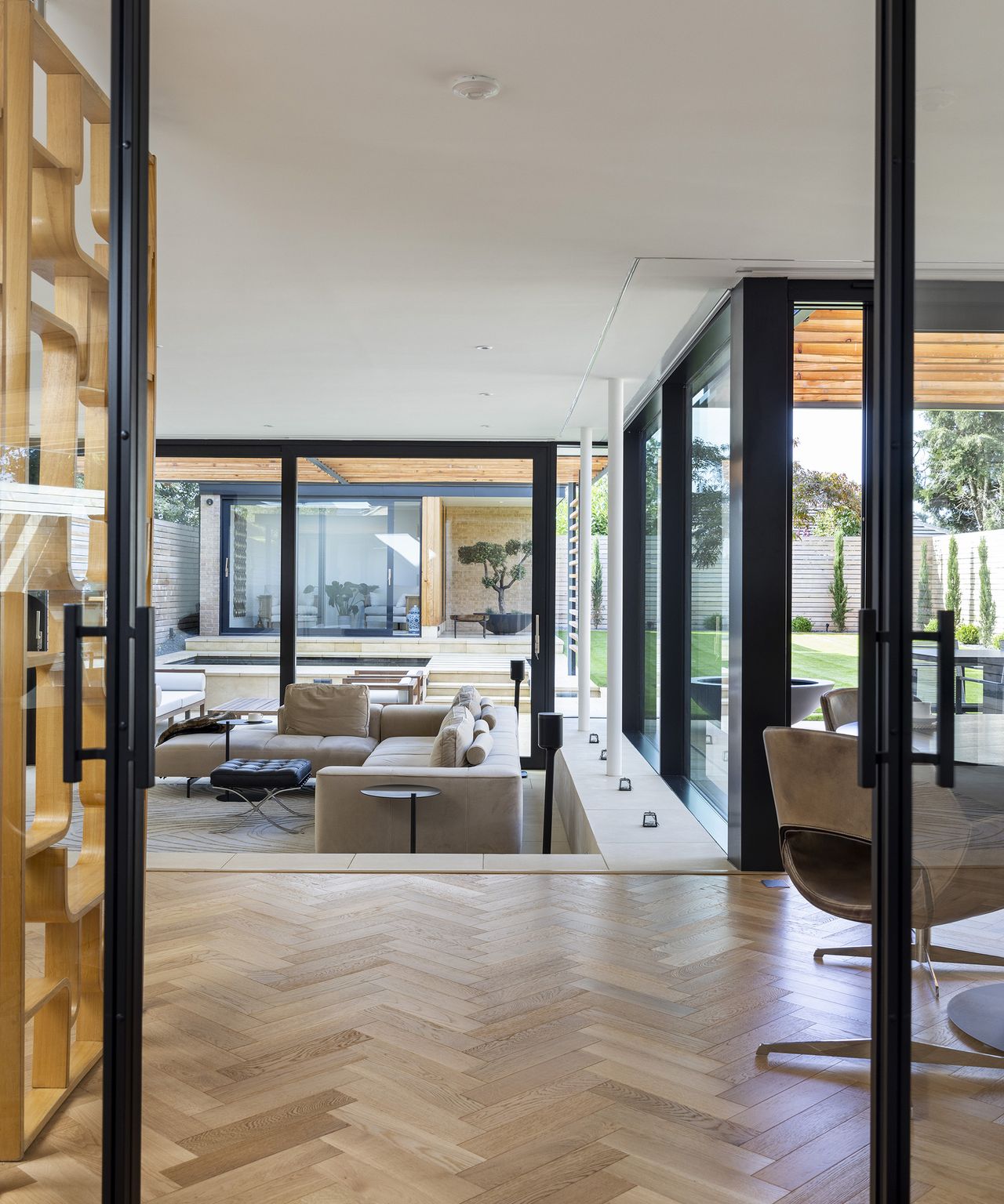 doors into an open plan living room, kitchen and dining room with wooden parquet flooring
