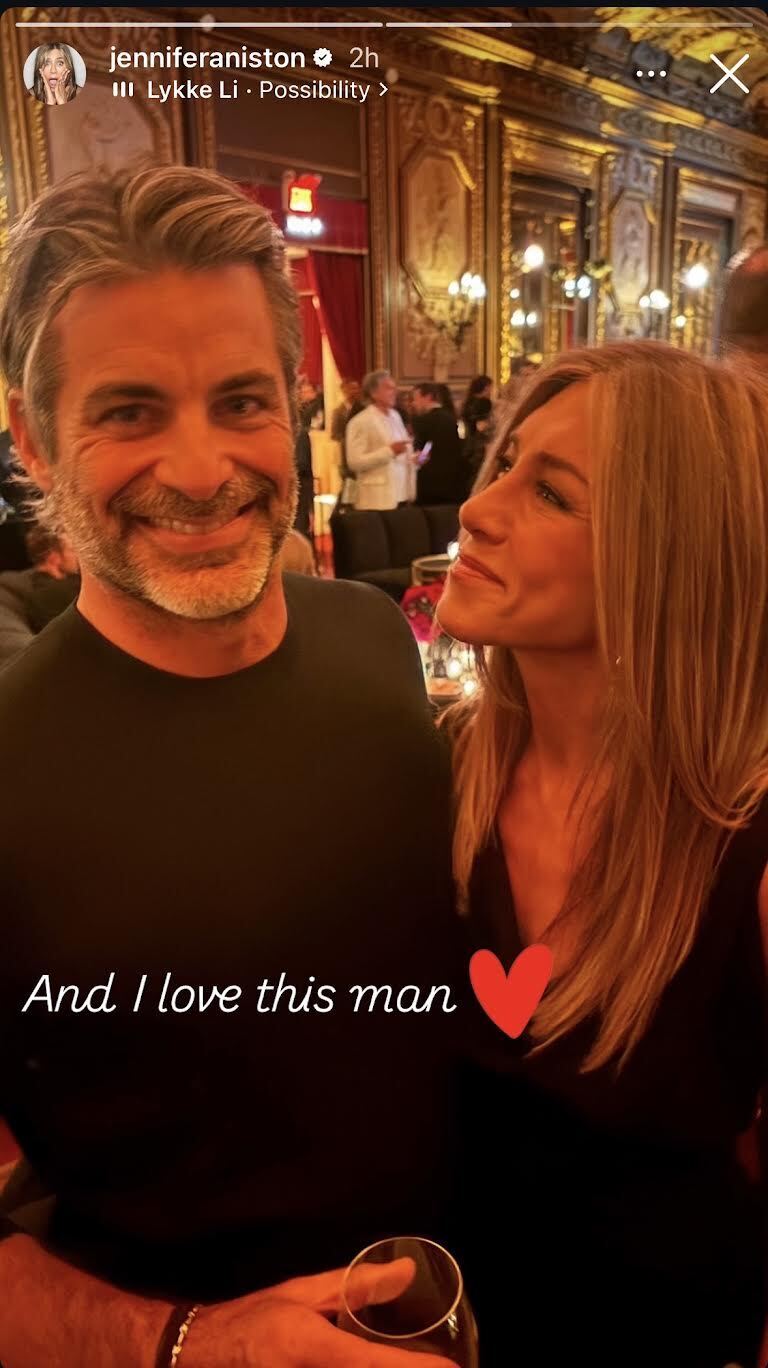 Jennifer Aniston standing next to her boyfriend, Jim Curtis, both wearing black, as well as sharing his new book, which she says she loves.