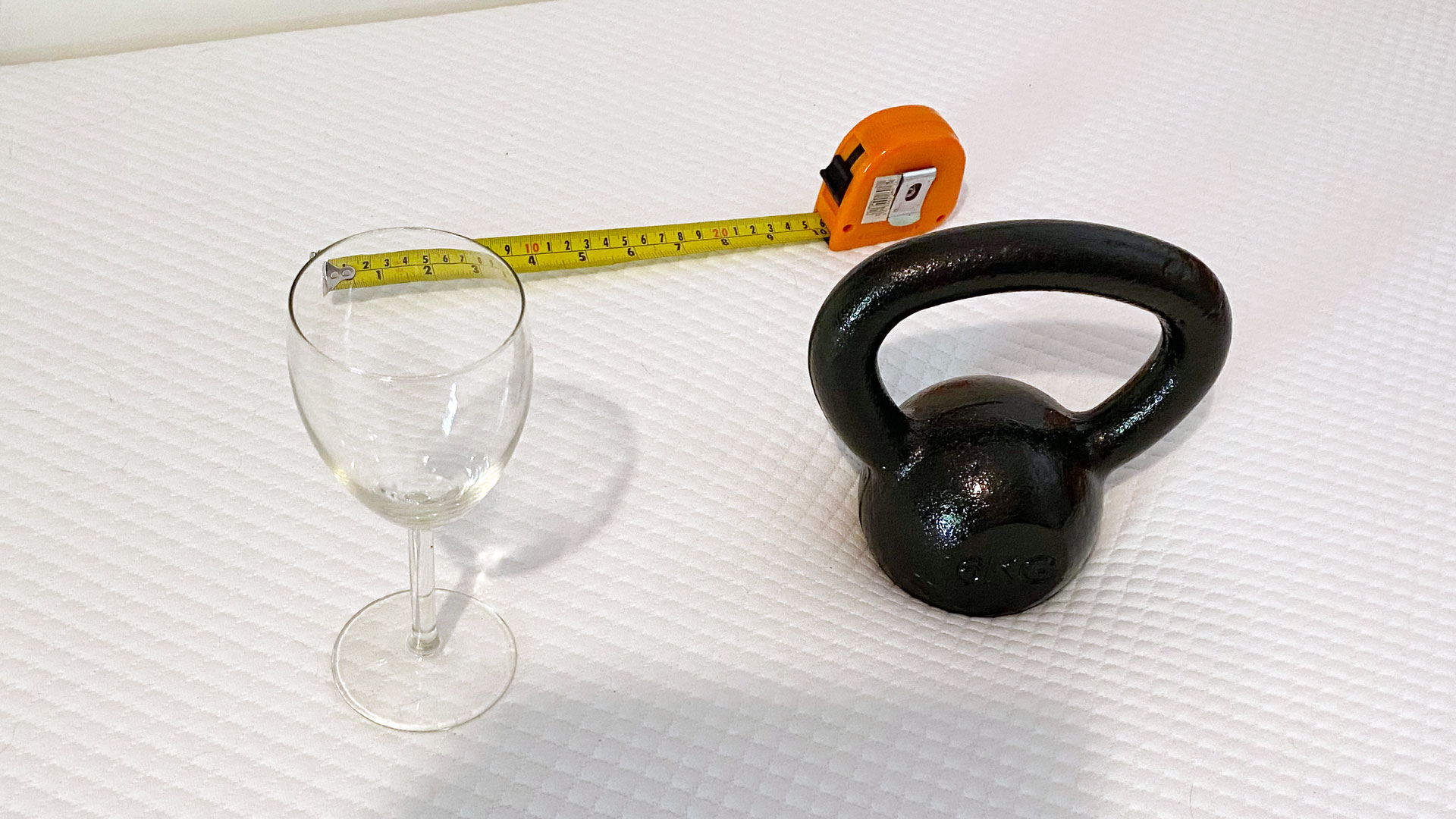 A weight, a wine glass and a tape measure on a Simbatex Foam Mattress