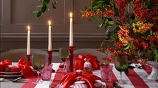 Red and white striped tablecloth with red taper candles, red napkin bows, and a fall centerpiece