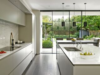 large modern white open plan kitchen diner with large bifold doors by brayer design, a large island, leading out onto the garden
