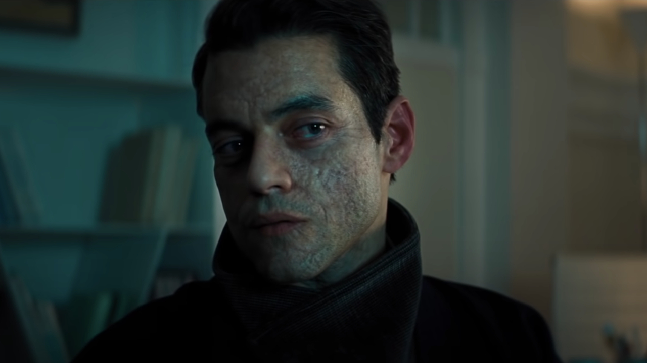 Rami Malek looks coolly towards the screen in No Time To Die.