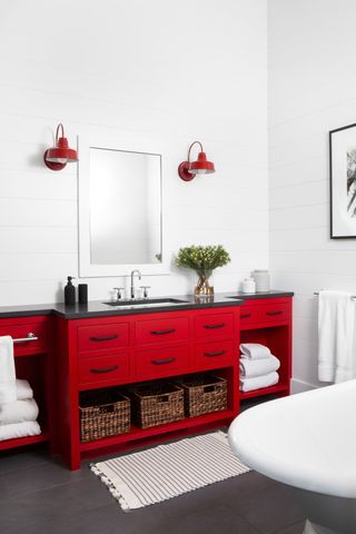 A red and white bathroom idea with red vanity and wall lights