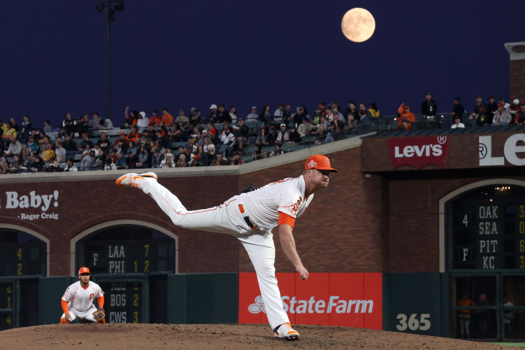 Een gigantische blauwe maan schijnt boven een honkbalwedstrijd terwijl de speler naar voren springt.