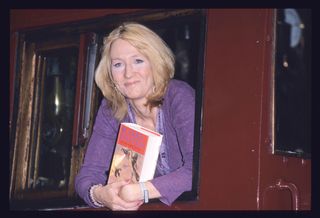 J.K. Rowling leaning out of a train window with a Harry Potter book