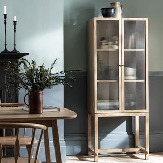 pale blue and green dining room with an oak reeded glass fronted display cabinet